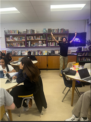 1 students standing looking excited while several students are sitting.